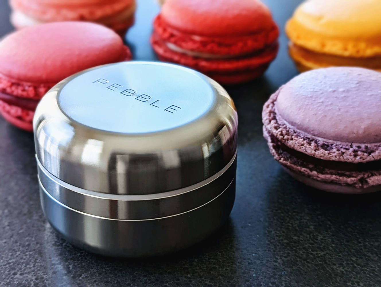 Pebble lifestyle image showing the Pebble Grinder among colorful macarons